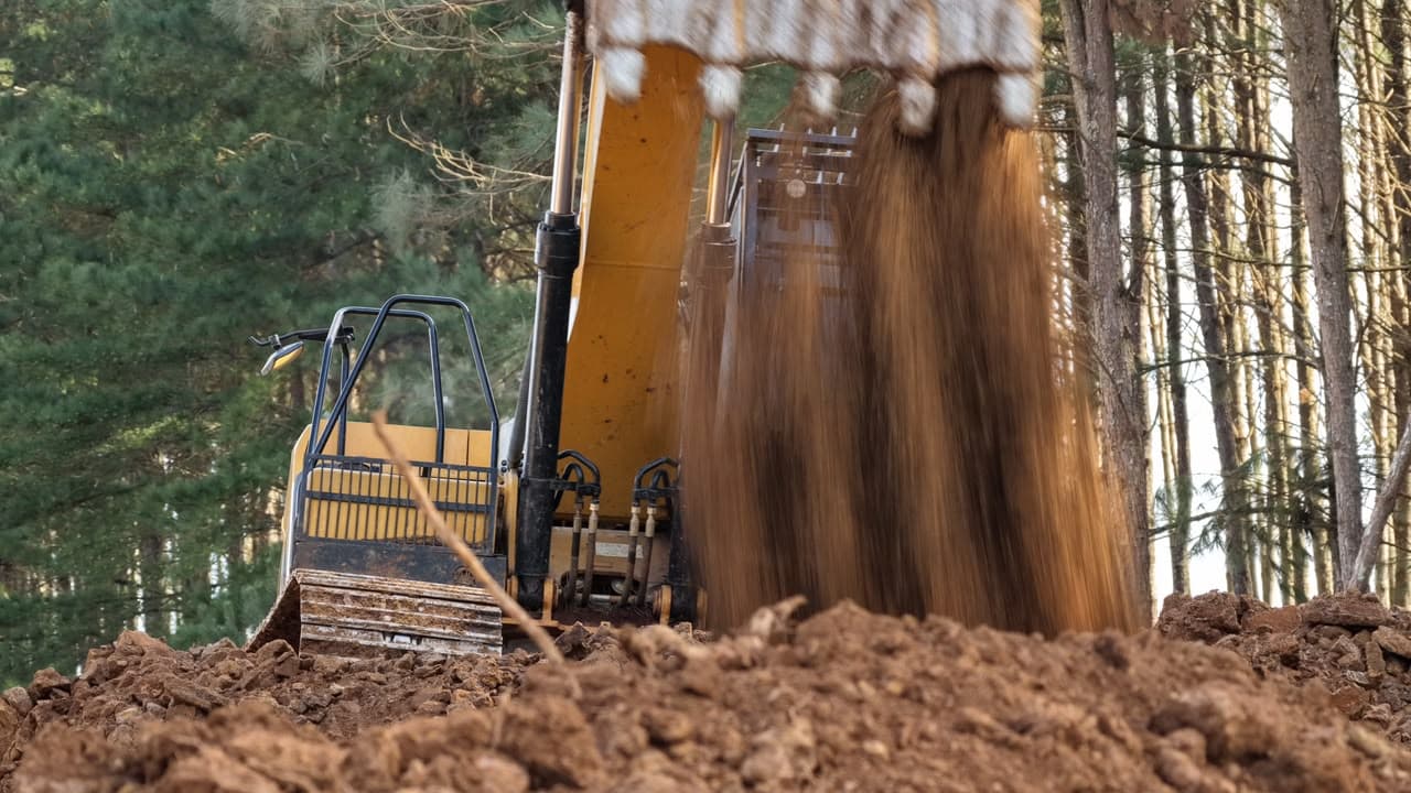Caçamba da escavadeira basculando material extraído